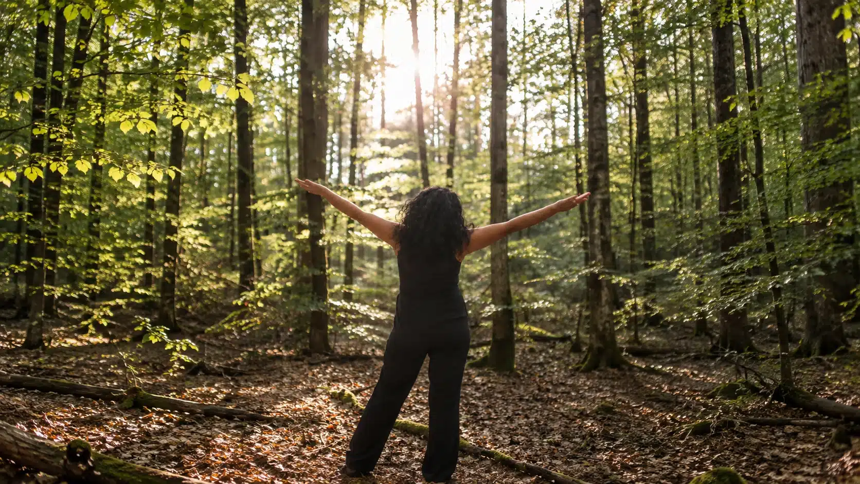 Eva Förtsch, Diplom Psychologin in Bamberg und online, steht mit ausgestreckten Armen in einem sonnigen Wald.